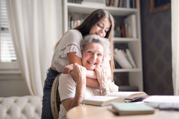 A young girl hugs an old woman