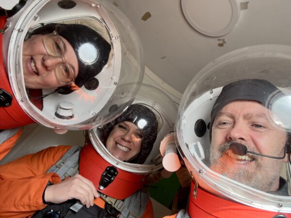 Three people in space suits taking a selfie.