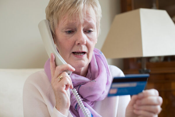 Elderly woman giving credit card details over the phone.