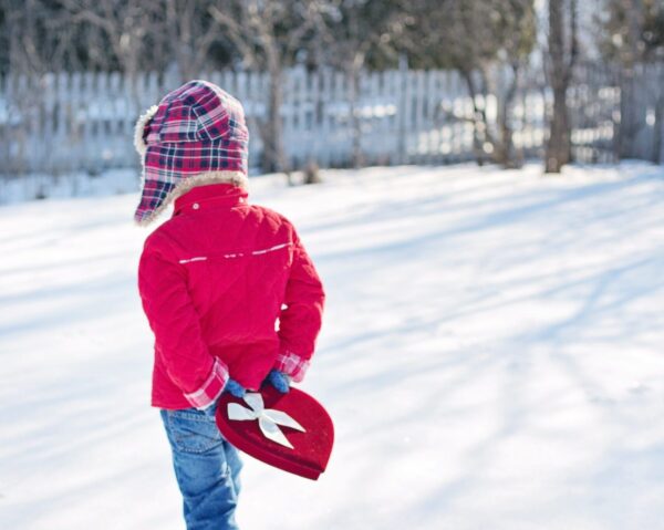 Kid walking through snow holding a heart-shaped box