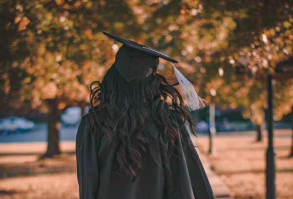 College graduate walking down a sidewalk.