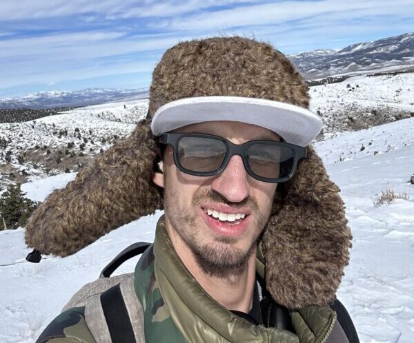 Austin Madsen. Brown stubbly beard. Winter hat with ear flaps.