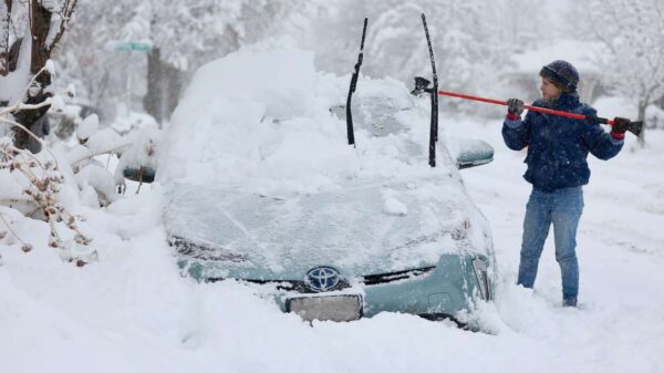 A woman clears over a foot of snow off her car in Salt Lake.