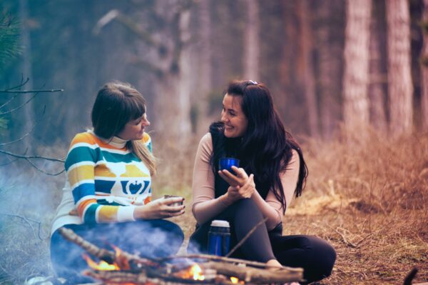 Two women talking by a campfire.