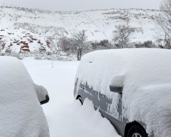 Snow heavily covering two cars in Cannonville, Utah.