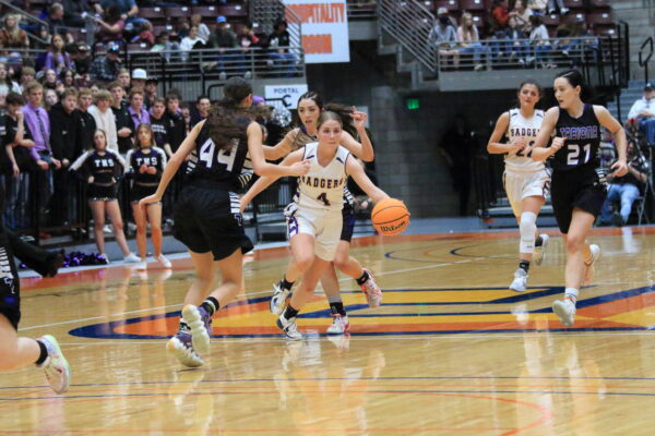 Number 4 charges down the court with the ball.