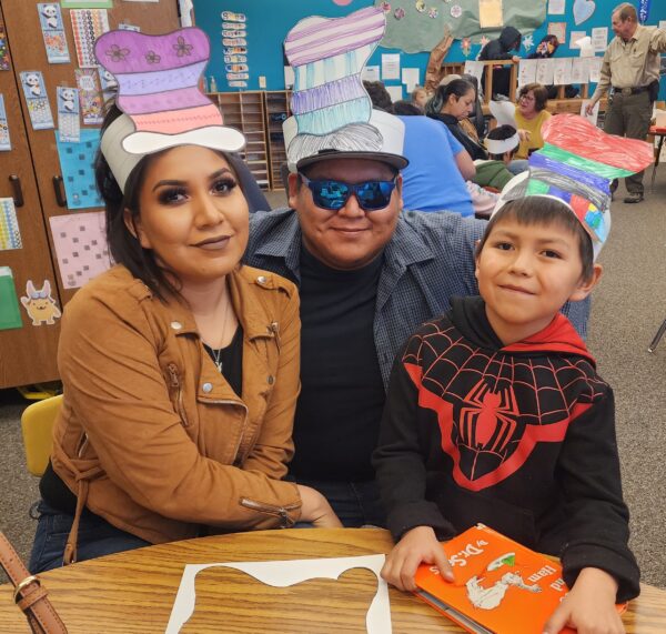 Two parents and a child in colored, paper "Cat in the Hat" hats.