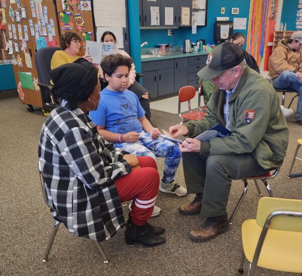 Three people reading together in a classroom at Lake Powell School.