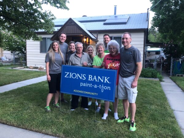 A family holding a Zions Bank Paint-a-Thon poster.