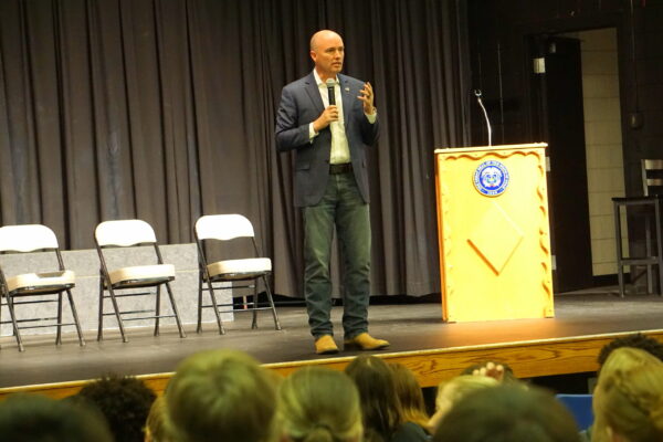 Governor Cox speaks on a stage to Piute High School.