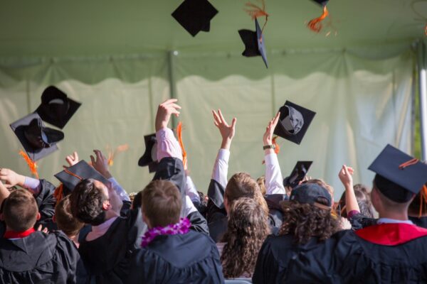 A graduating class throws their caps in the air.