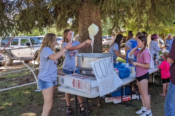 Girls pass out freshly spun cotton candy to customers.