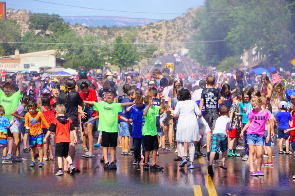 A firehose soaks 1000s of people on Escalante Main Street during their Pioneer Day celebration.