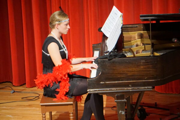 Nadia Griffin plays piano, dressed in 1920s attire, for the Escalante 100-year reunion.