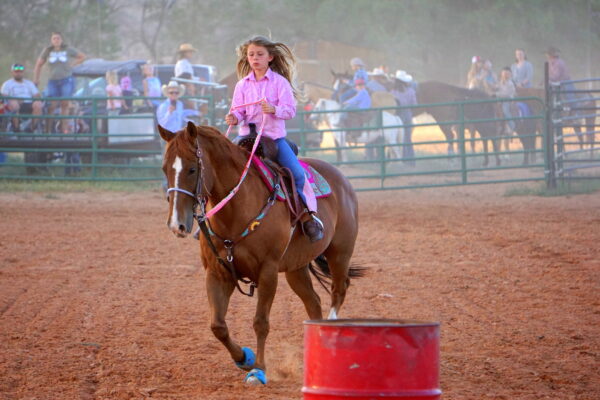 An elementary-aged girl does barrel riding in the Escalante Pioneer Day rodeo.