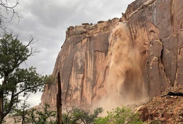 A flash flood waterfall falling off a red cliff in Capitol Reef National Park.