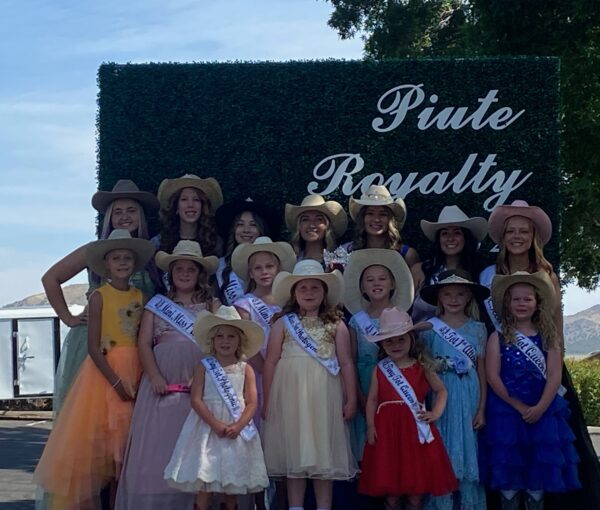 A group of girls in dresses, sashes and cowboy hats.
