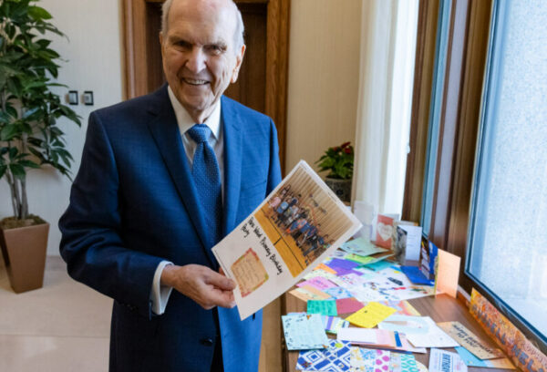 President Nelson holding a card from a primary-aged child at a desk in the Church Office building.