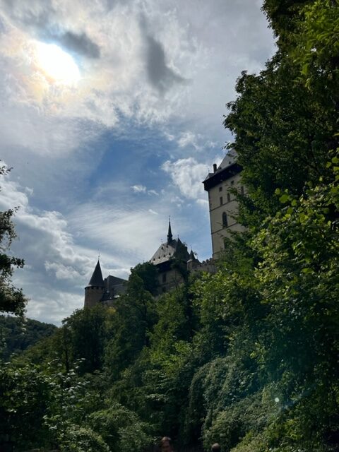 The Karlstejn Castle peaking out from behind green trees.
