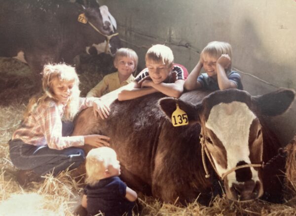 Five kids lounge around with a cow during a 1982 livestock show.