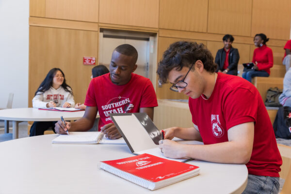 Two young men work on homework in an SUU commons.