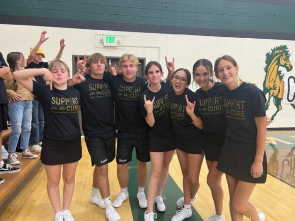 Cheerleaders in gold and black t-shirts reading, "support for the cure, childhood cancer."