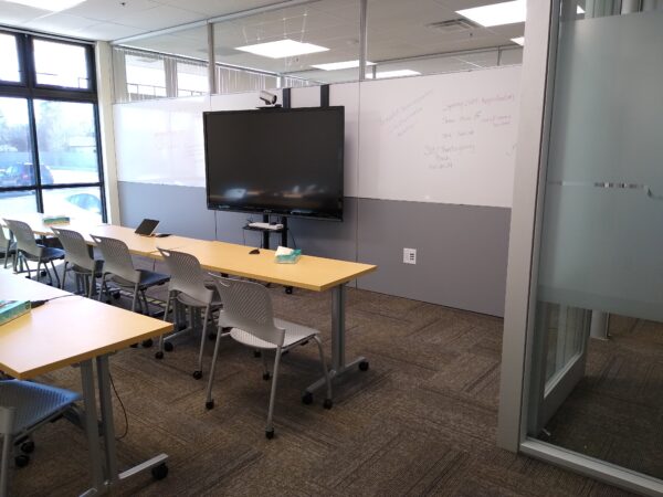 A classroom with window lighting, a TV, and glass walls.