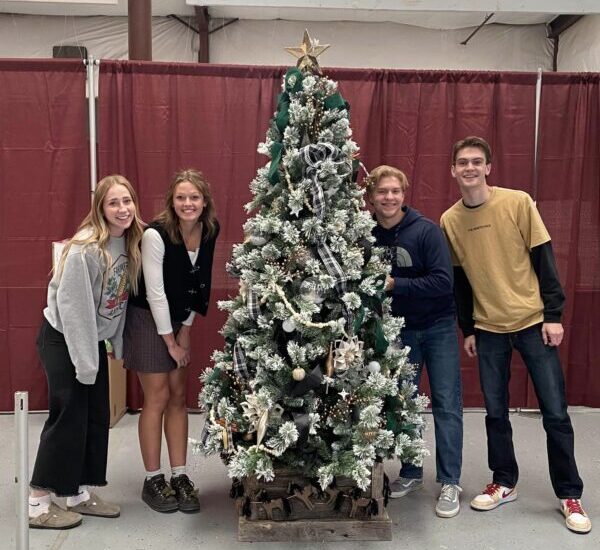 The four people in the Bryce Valley High School student council stand next to their school's tree at the festival.