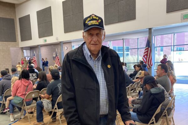 An elderly man in a "WWII Veteran" hat.