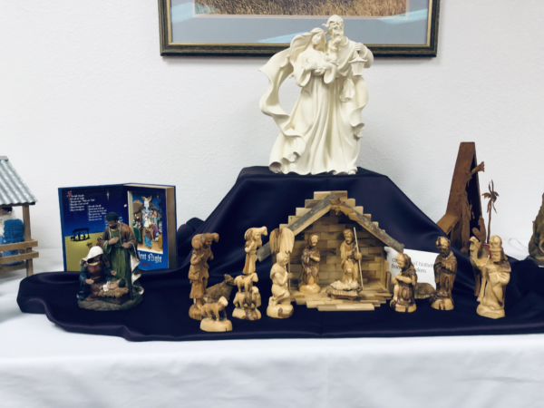Various nativity sets decorate a white-clothed table.