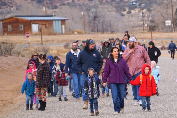 A crowd of elementary school students and adults walks down the street.