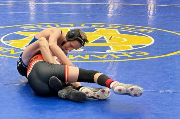 A Panguitch wrestler holds a Monticello wrester in a hold between his legs.