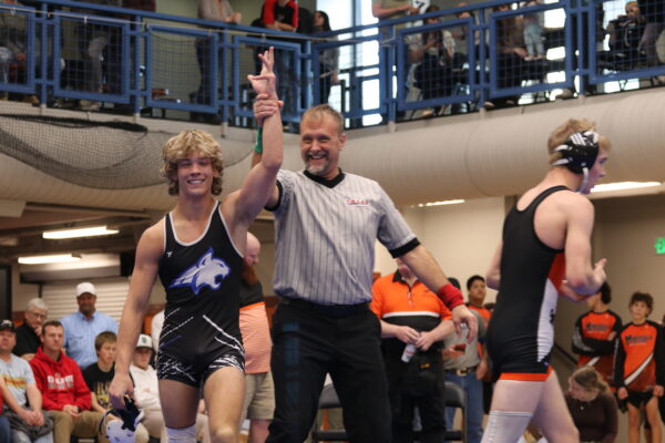 A referee holds up a Panguitch wrestler's hand to indicate the winner of the match.