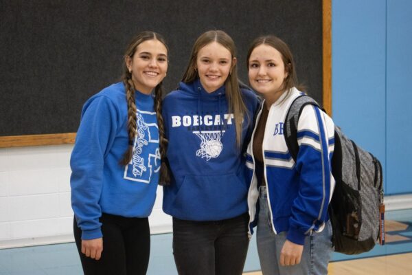 Three high school girls in blue Bobcat sweaters.