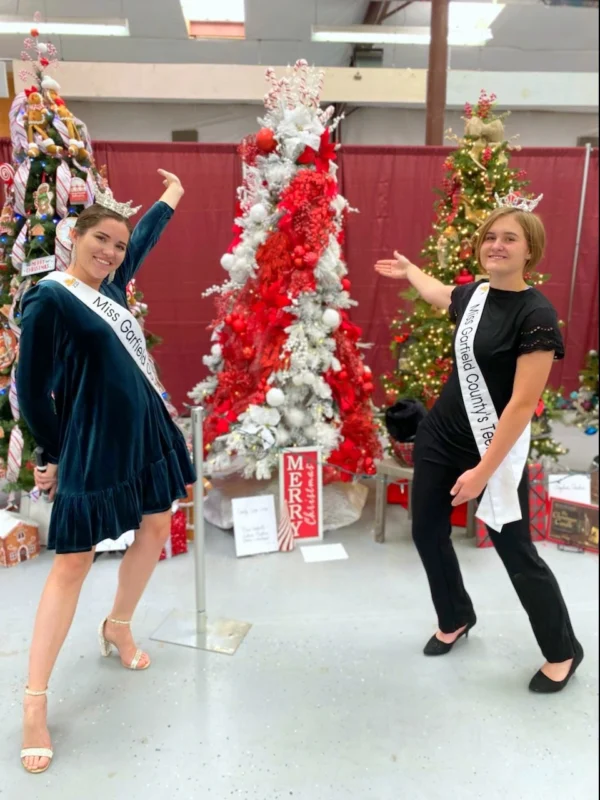 Miss Garfield and Miss Garfield's Teen (wearing sashes and crowns) show off their tree at the Panguitch Festival of Trees.
