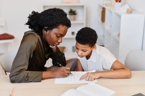 A woman and a boy work on homework together.
