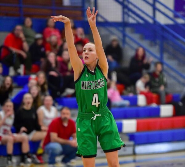 A girls basketball player from Bryce Valley jumps, flicking her hand as she sends off a shot for the hoop.
