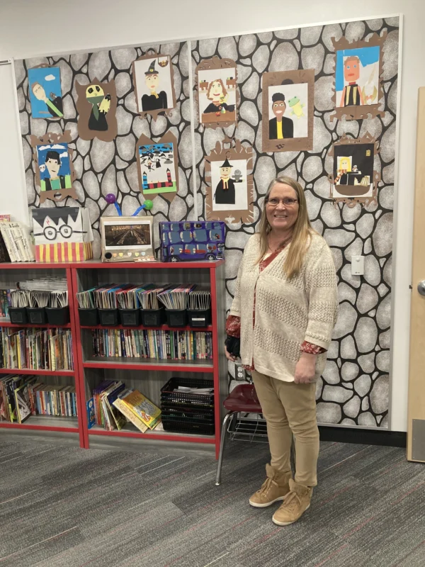 A woman standing by colorful book selves and artwork at the new Escalante Elementary School.
