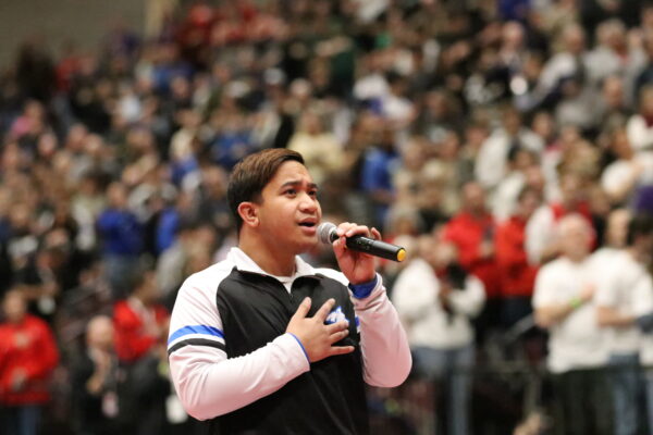 Jaren Henrie holds his hand over his heart as he sings the national anthem.