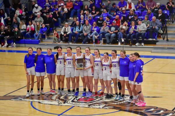 The Panguitch girls basketball team takes a group photo on the court with the region trophy.