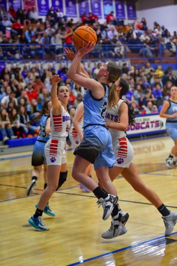 A Piute girls basketball player goes in for a layup as Panguitch players try to block her.