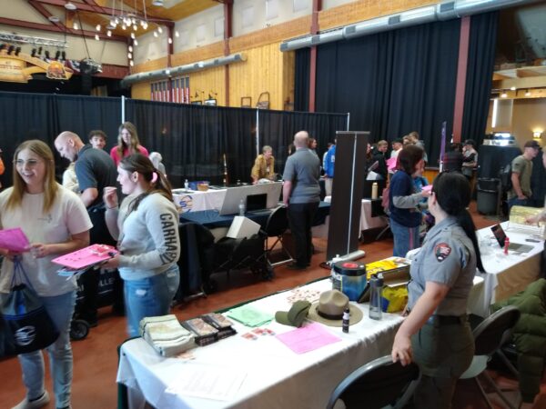 High school-aged kids walk around looking at different vendors' booths at a career fair.