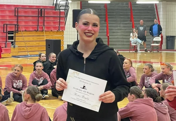 Kirsten, covered in makeup, smiles with her award after a drill competition.