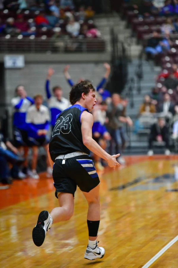 A Panguitch boys basketball player yells as he runs down the court.
