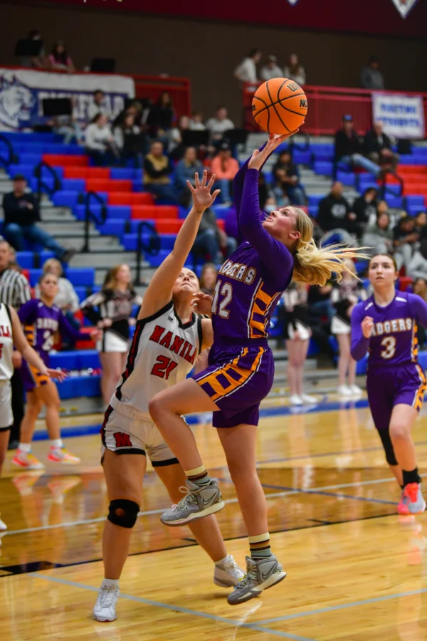 A Wayne girls basketball player goes for a layup with some difficulty right in front of the basketball hoop.