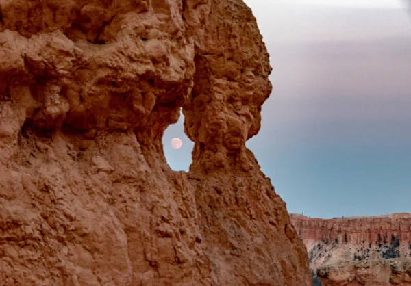The full moon through a window in the red rock.