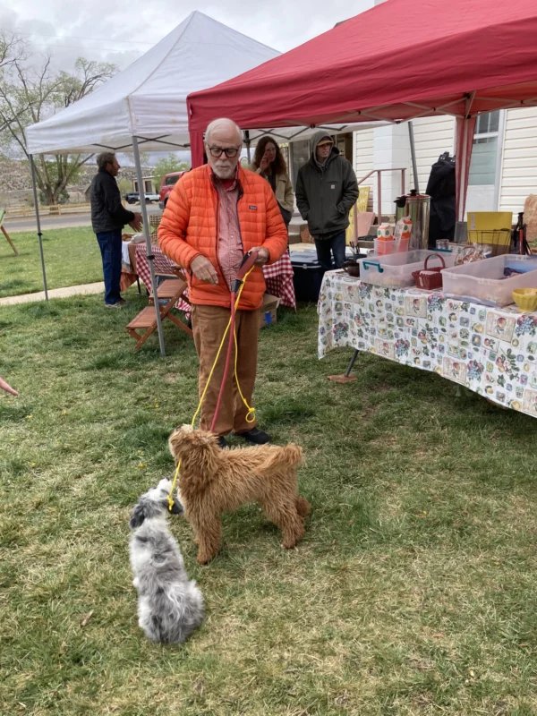 A man holds a dog on a leash as it visits with another dog at the Escalante farmer's market.