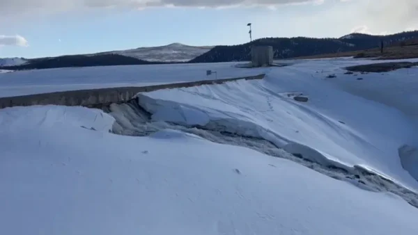 Water flows through the dam wall surrounded by snow at Panguitch Lake.