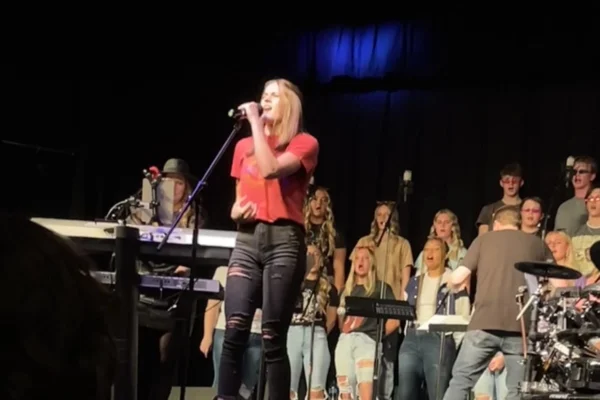 Katie Snyder moves her hands with feeling as she sings at the microphone in front of the choir.