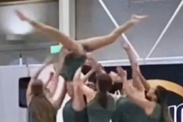 Piute dance company lifts a girl upside-down above their heads as she does the splits.